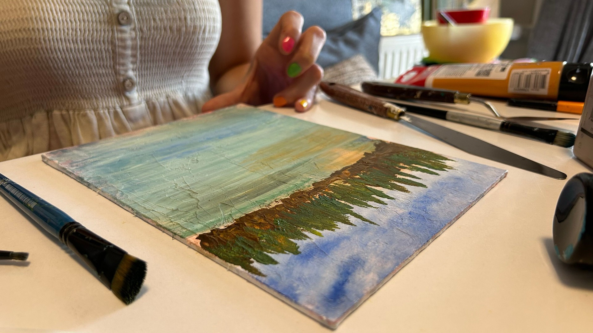 A close-up of a female painter working on a canvas with paints and brushes